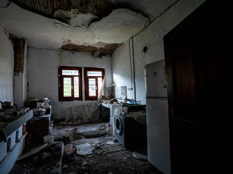 Gutted kitchen with torn-out ceiling and remodel debris